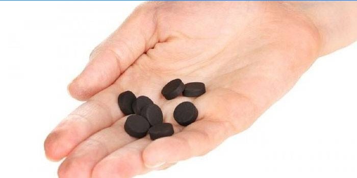Tabletten met actieve kool in de palm van je hand