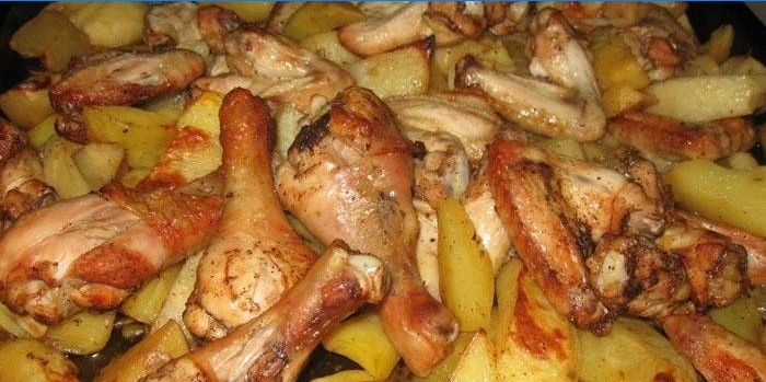 Kippenpoten met aardappelen op een bakplaat