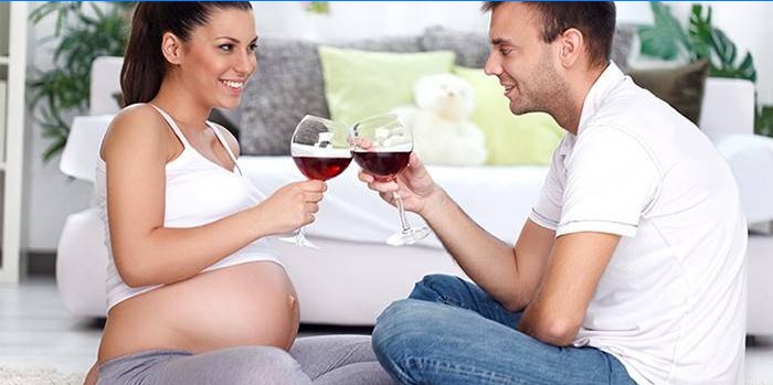Zwangere vrouw drinkt wijn in het gezelschap van een man