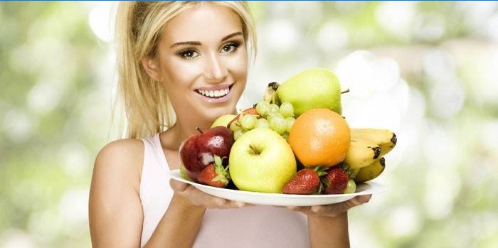 Meisje houdt een schotel met fruit en bessen.