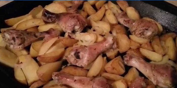 Kippentrommelstokken met aardappelen op een bakplaat