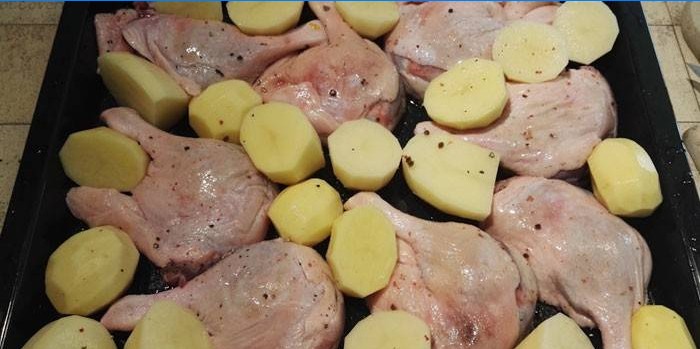 Eendpoten met aardappelen op een bakplaat voor het bakken