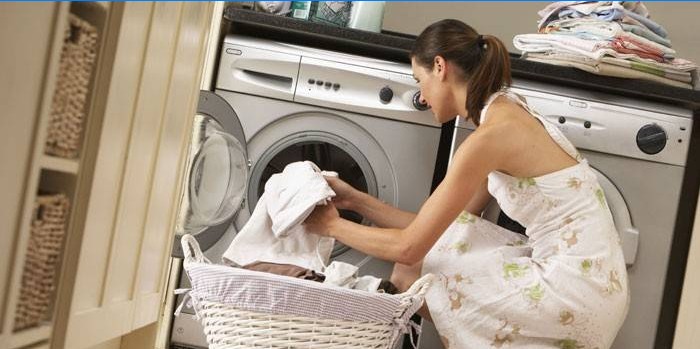 Meisje zet handdoeken in een wasmachine
