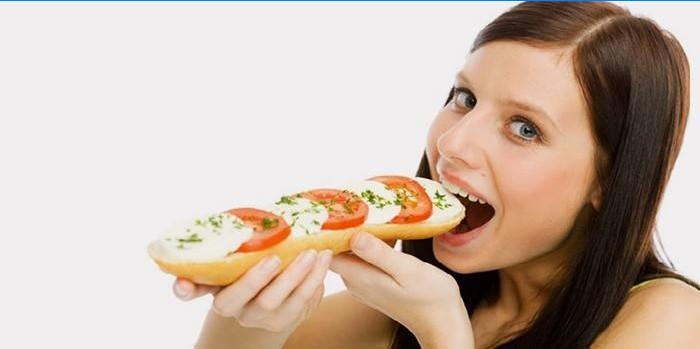 Meisje eet een broodje met tomaten en kaas