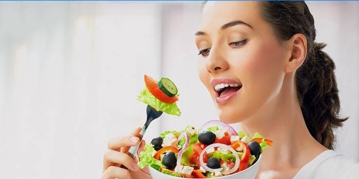 Meisje eet groentesalade volgens dieet voor vermagering van benen en heupen