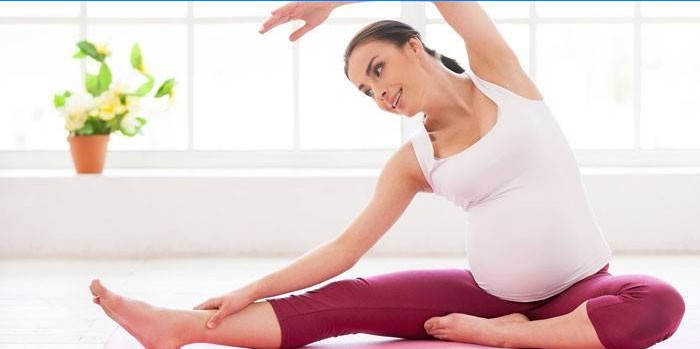 Zwangere vrouw voert een oefening terwijl zittend op de vloer
