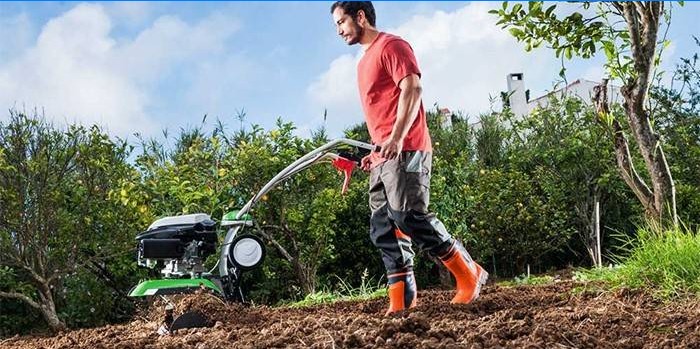 Een man graaft een tuin met een achterlooptractor