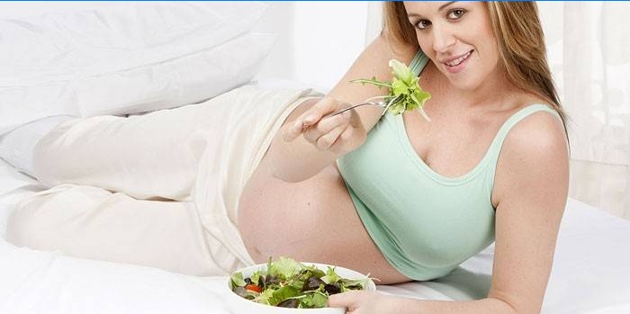 Zwanger meisje dat salade eet