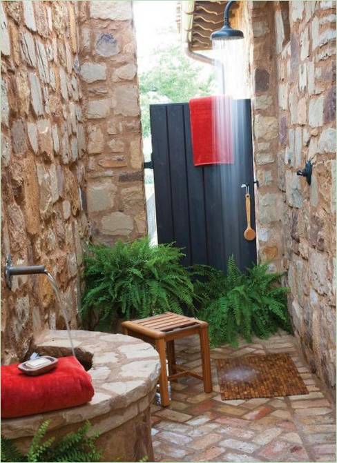 Douche met stenen muren en een houten deur