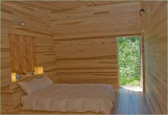 Helder bed in een slaapkamer met houten afwerking